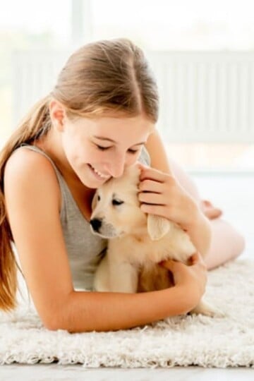 Emotional girl hugging retriever puppy