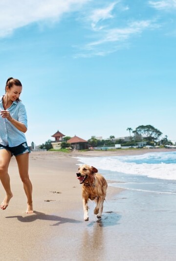 Woman running on the beach with her dog
