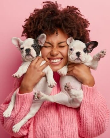 Woman holding two small puppies