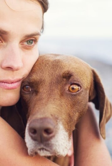 Woman hugging her dog close beside her