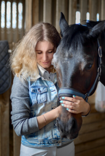 Woman with her horse inside a stable
