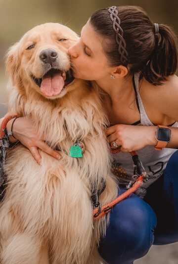 Woman hugging her large golden-colored dog