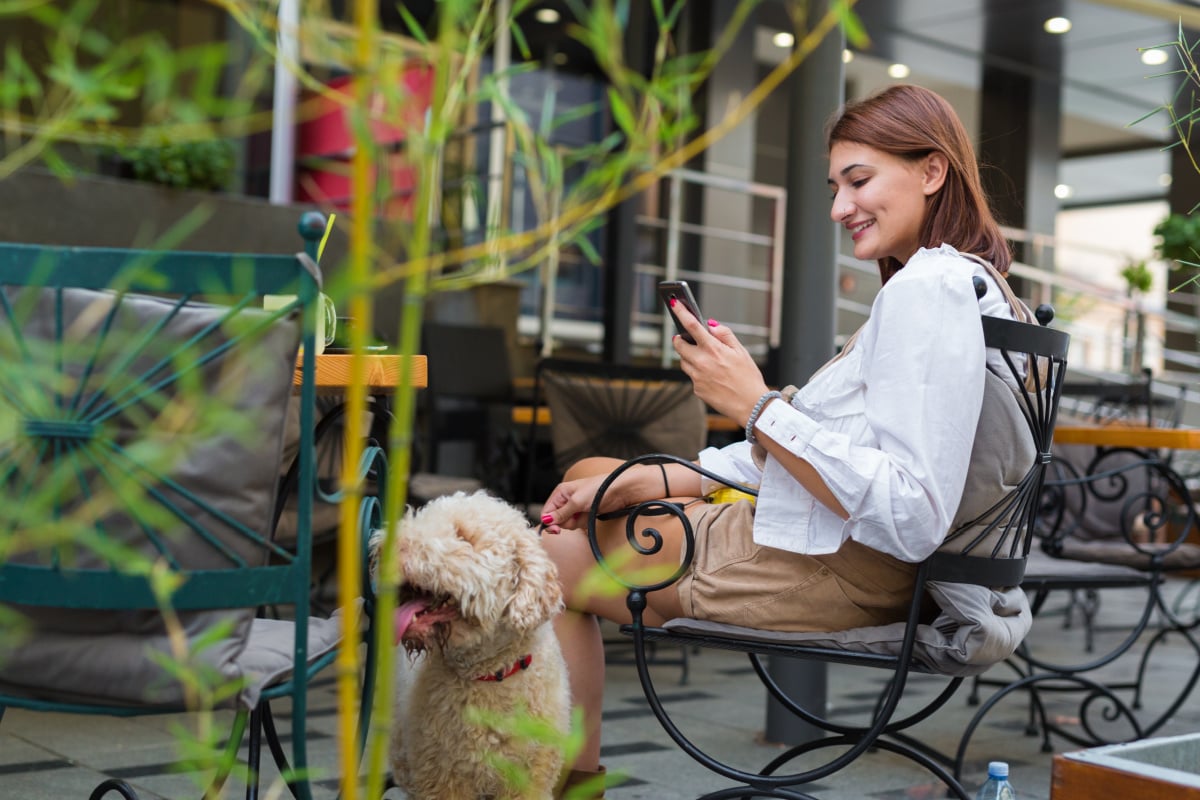 White poodle with a woman in an outdoor cafe